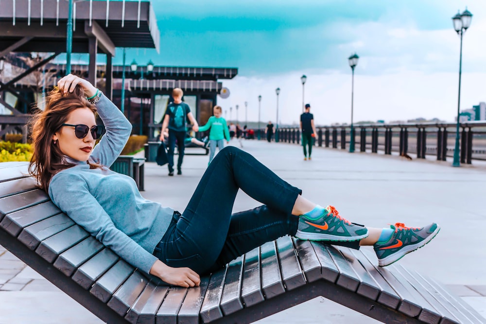 woman lying on lounge chair near people, lampposts, and handrail