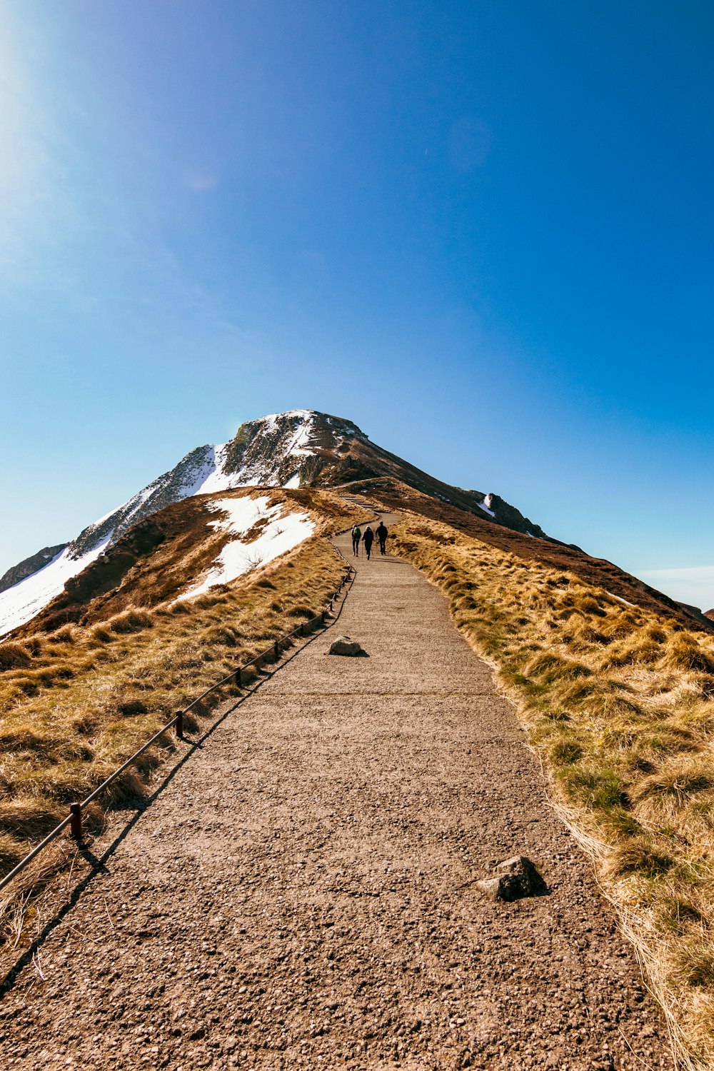 road leading to peak of rock mountain under blue sky