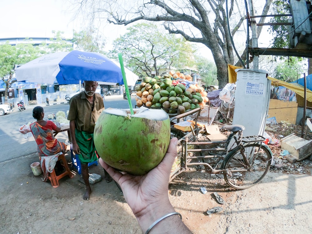 a man holding a green coconut in his hand
