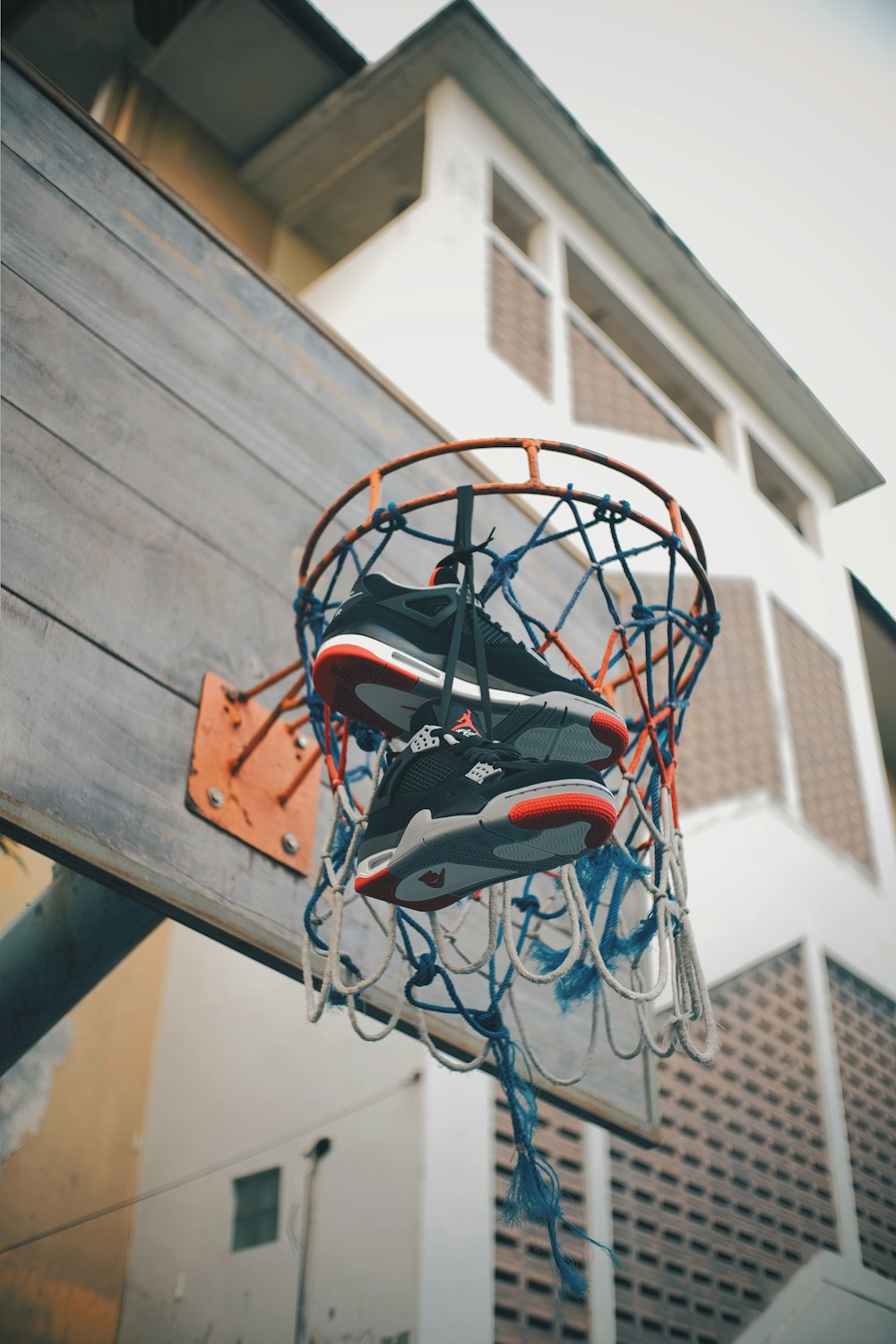 日中にネットにぶら下がっているバスケットボールフープのエアジョーダンシューズ