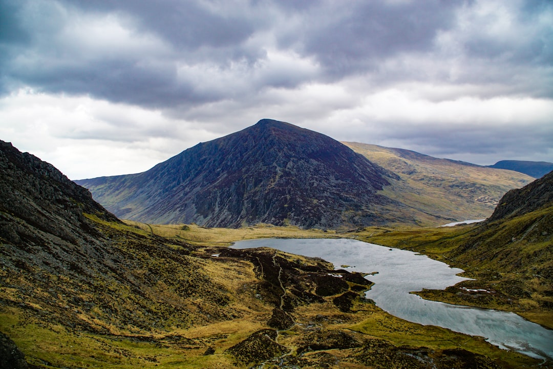 body of water passing by mountain under white cloud formation