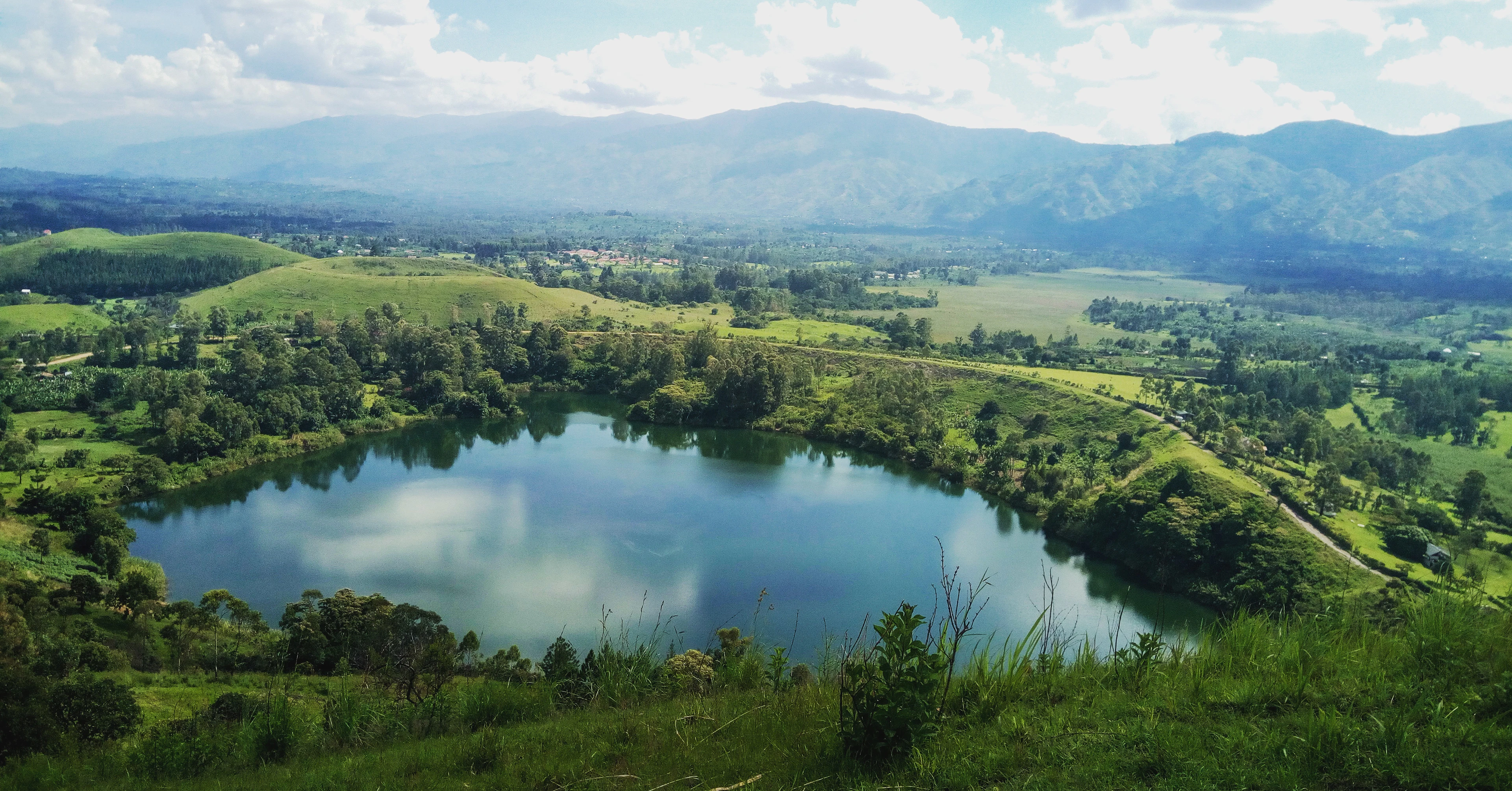 A crater lake among green hills and forest in Uganda