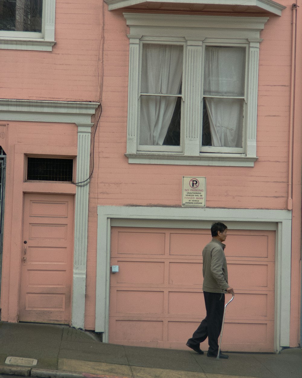 person walking near pink house