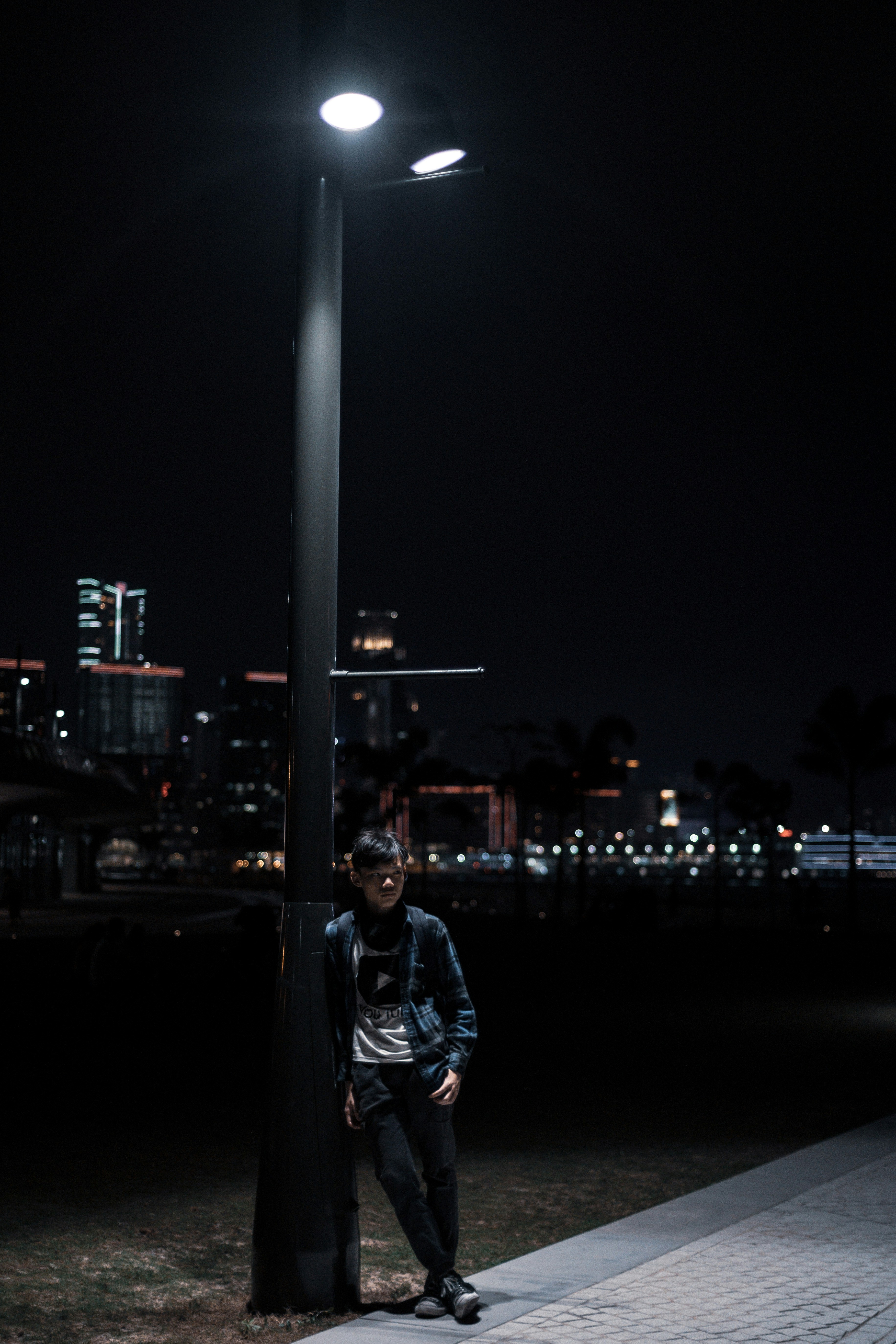 man leaning on light post during nighttime