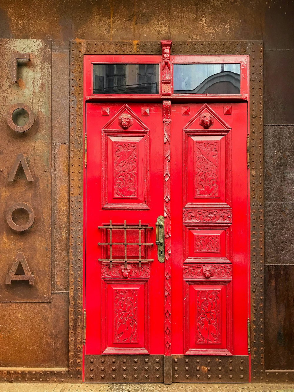 茶色の素朴な金属の壁に赤く塗られたドア
