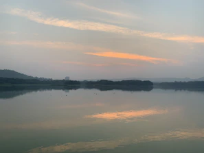 A quiet lakeside scene at dusk with gentle ripples and pastel skies