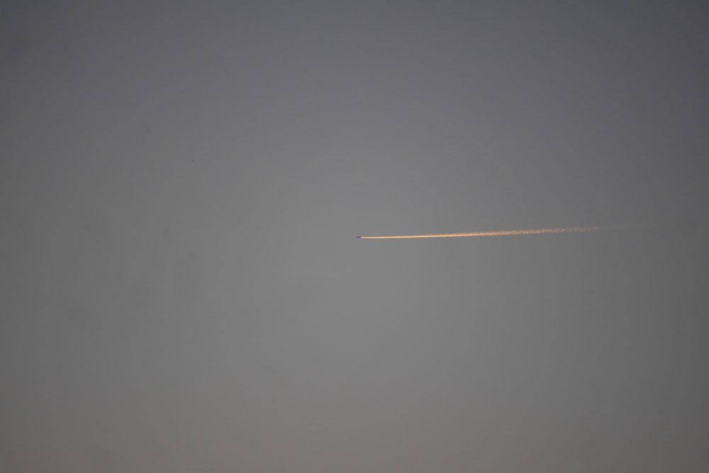 Um avião está voando no céu com um rastro de fumaça