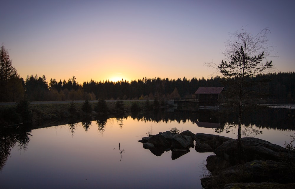 the sun is setting over a small lake