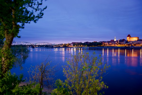 The old town lit up across the river — Toruń, Poland