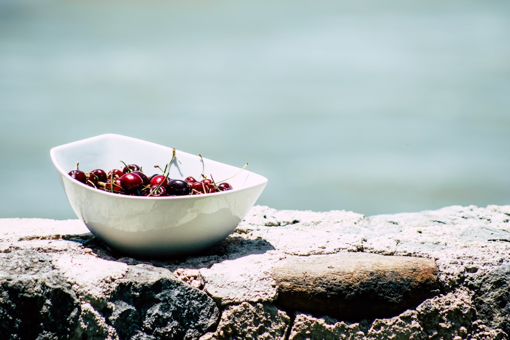 bowl of red berries on rock