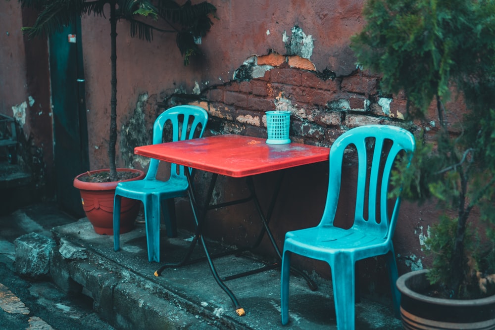 red and black folding table with between two blue plastic chairs