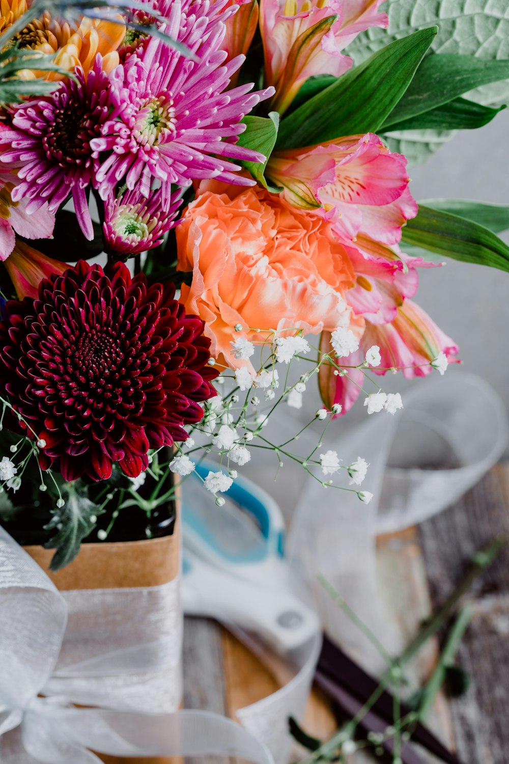 red, pink, and orange petaled flowers near wall