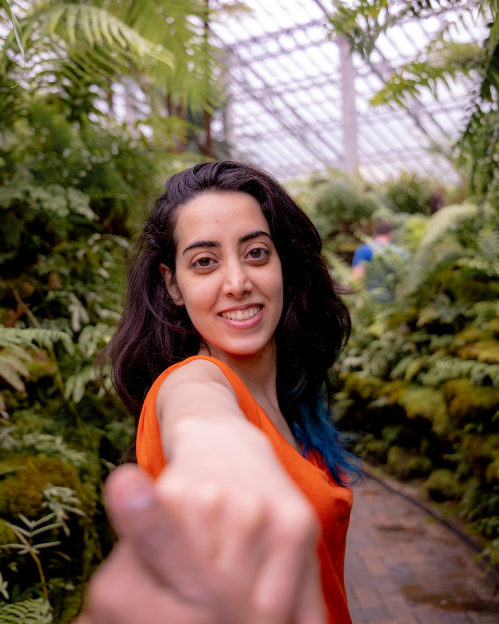 woman wearing orange sleeveless top standing in greenhouse