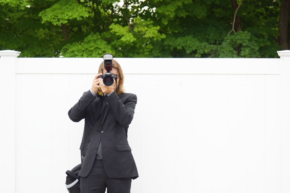 person in black suit jacket using DSLR camera