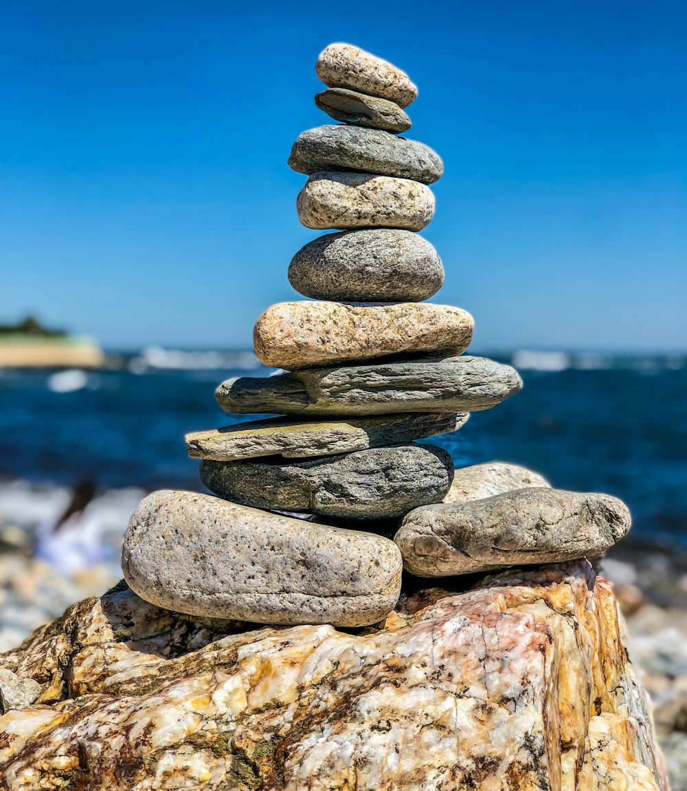 grey rocks stacked on large rock at the beach