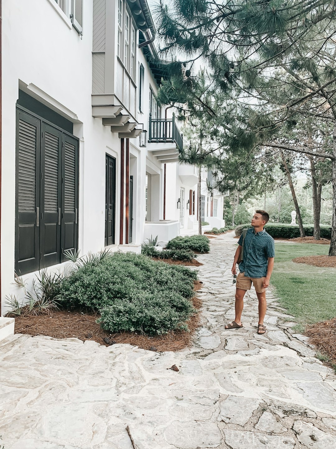 man standing outside the building near trees