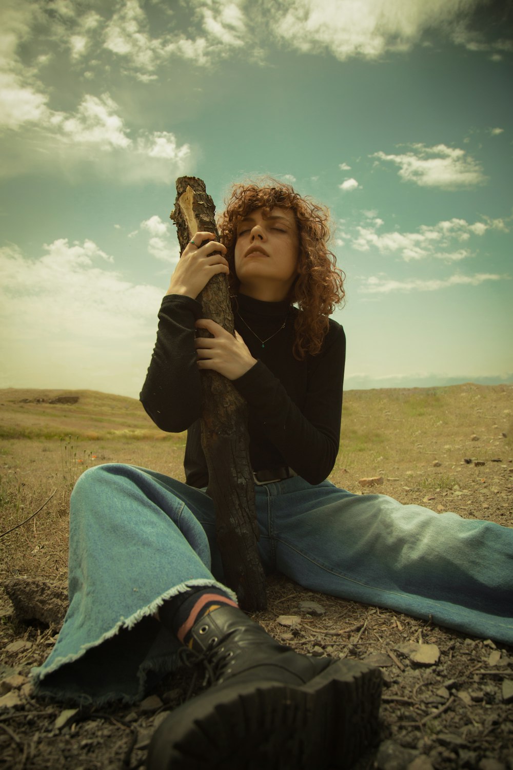 woman holding tree log sitting on ground