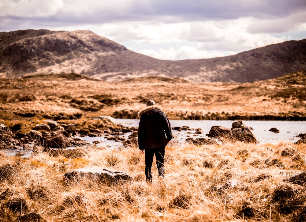 man wearing black jacket standing on grass field