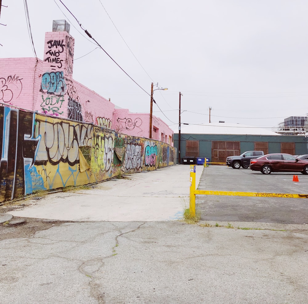 parked car lot beside graffiti wall during daytime