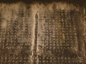 Vertical columns of ancient script cover a weathered stone surface, with faded and unevenly colored sections suggesting age and wear.