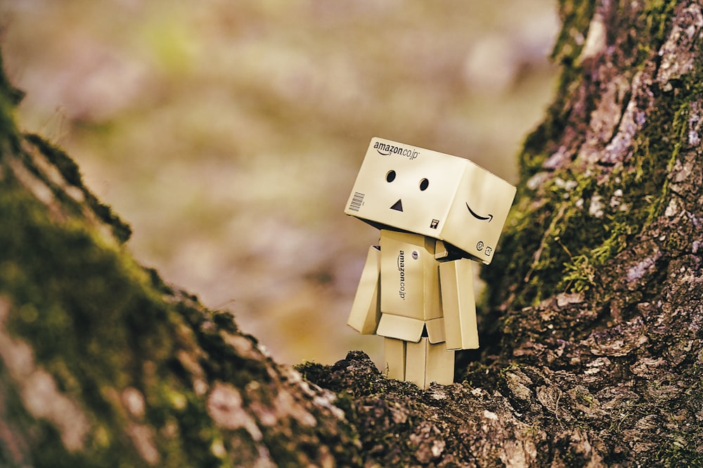brinquedo robô de papelão na árvore de madeira