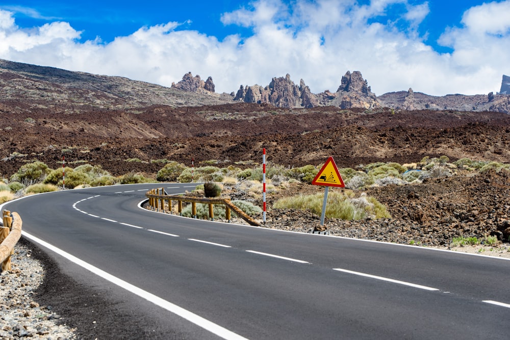 road with rail and sign near mountains during day