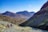 A group of hikers resting beside a serene mountain lake under clear blue skies.
