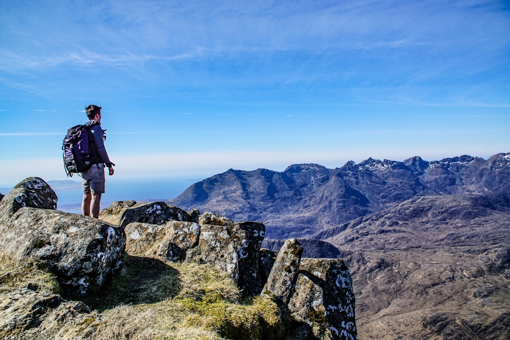 person in blue long-sleeved shirt standing on cliff