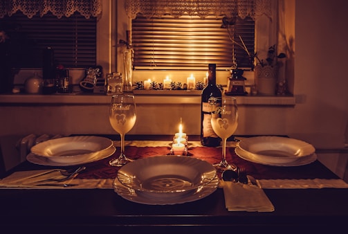three sets of plates, two wine glasses, and bottle of wine on table