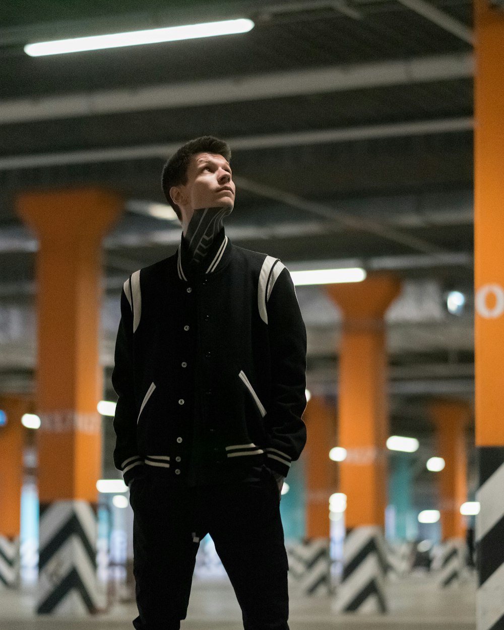 man in black and white jacket standing at basement parking