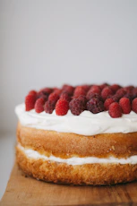 round cake with white frosting topped with red raspberries