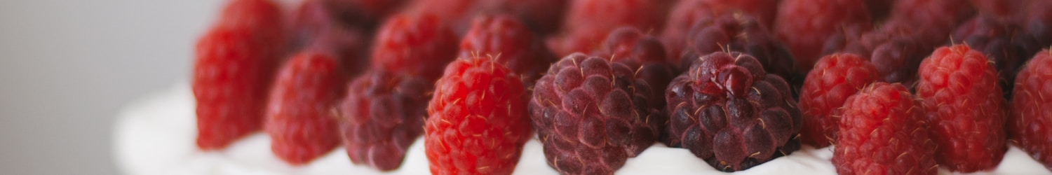 round cake with white frosting topped with red raspberries