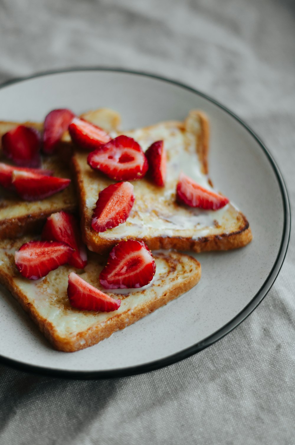 plate of toasted breads topped with sliced strawberries