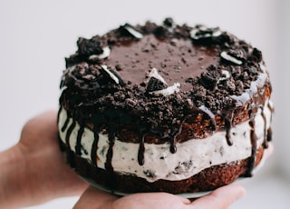 naked drapery chocolate cookies and cream cake on person's hands