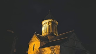 An elegant nighttime shot of the Lady of Lebanon Church illuminated softly in warm lights against the Miami sky.