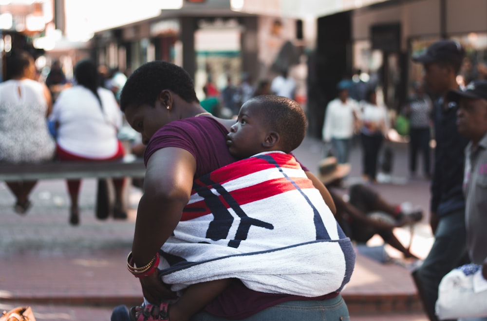 selective focus photography of woman carrying child