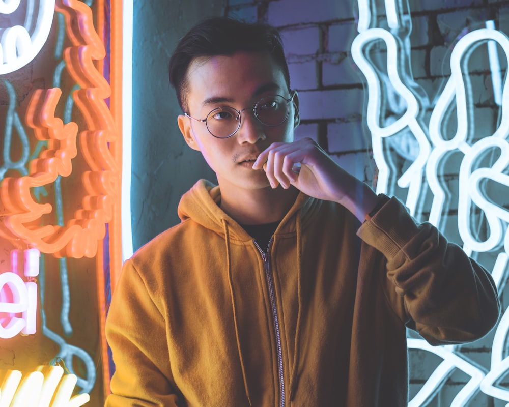 man in yellow zip-up hoodie standing near neon signages