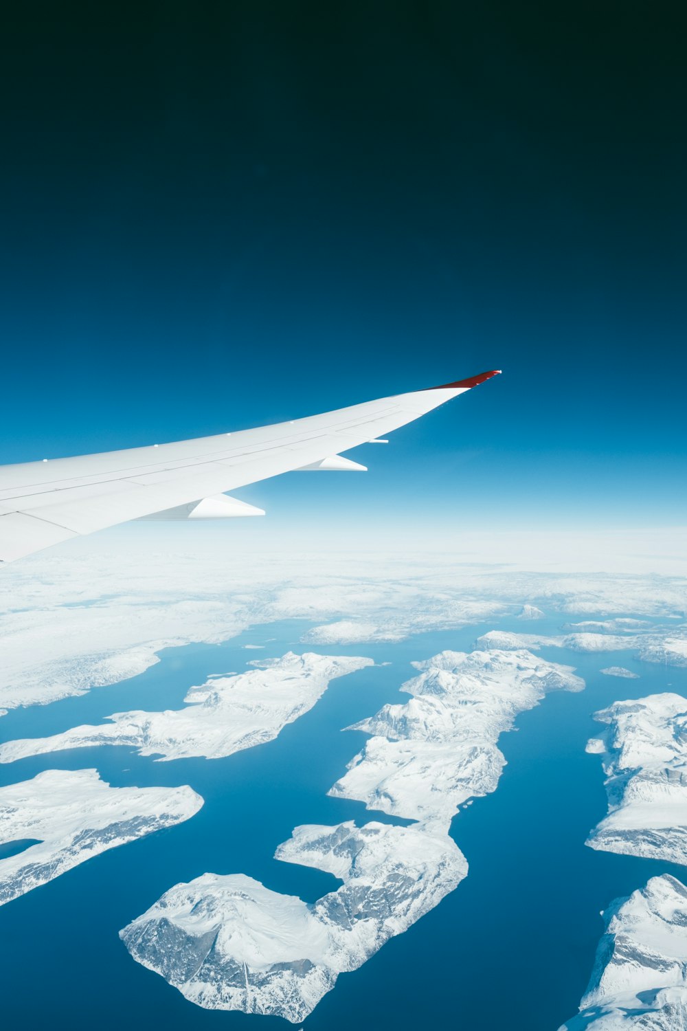 white airplane over rock mountains and blue sea