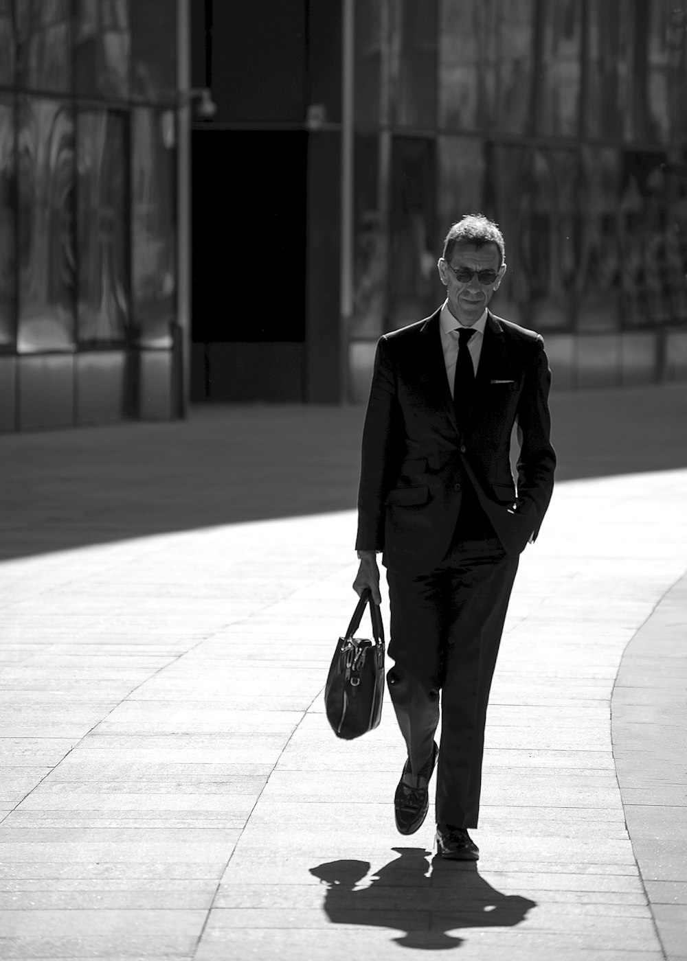 grayscale photography of man carrying bag