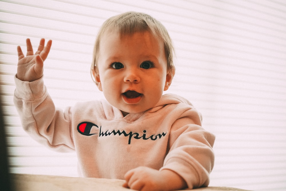 白いチャンピオンプルオーバーパーカーを着た笑顔の幼児