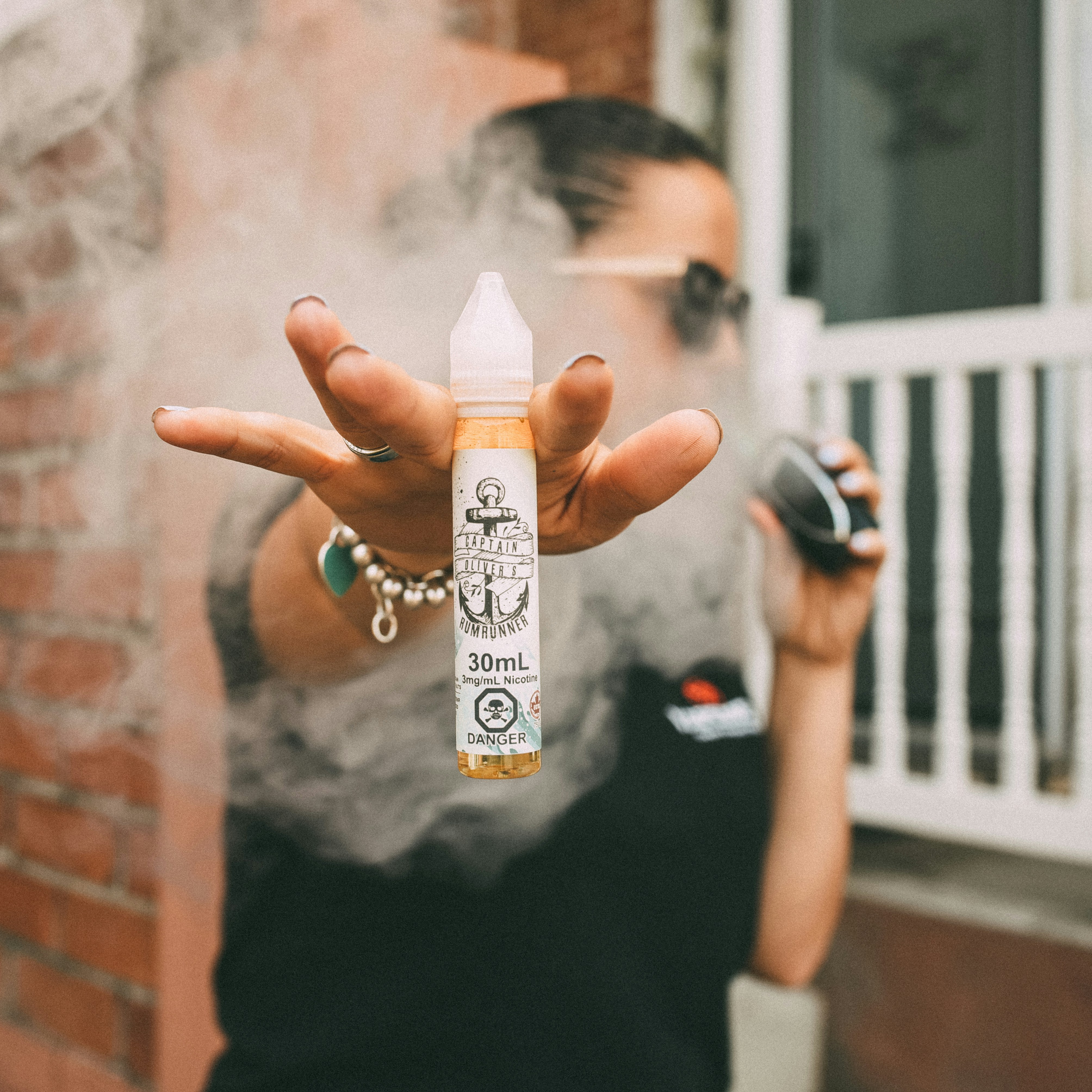 pessoa vaping segurando garrafa de suco eletrônico