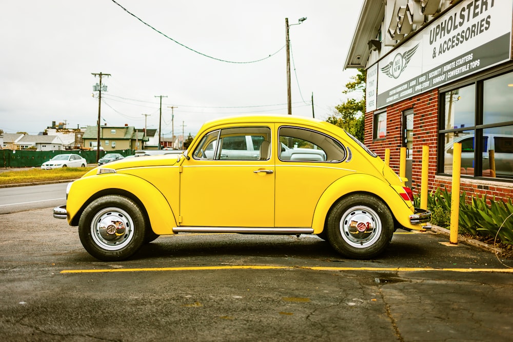 yellow Volkswagen Beetle coupe parked near building