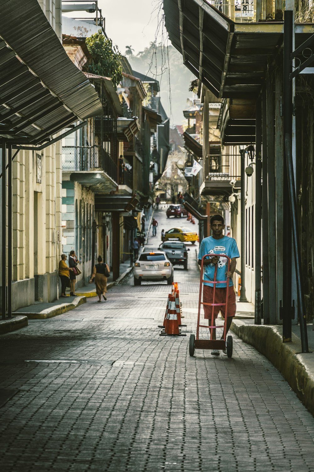 man wearing blue crew-neck shirt pushing handtruck