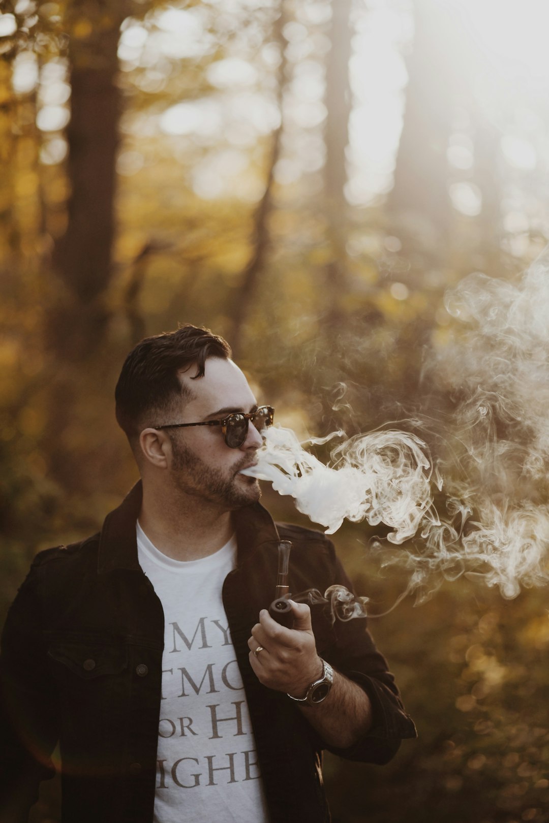man wearing black jacket holding smoking pipe