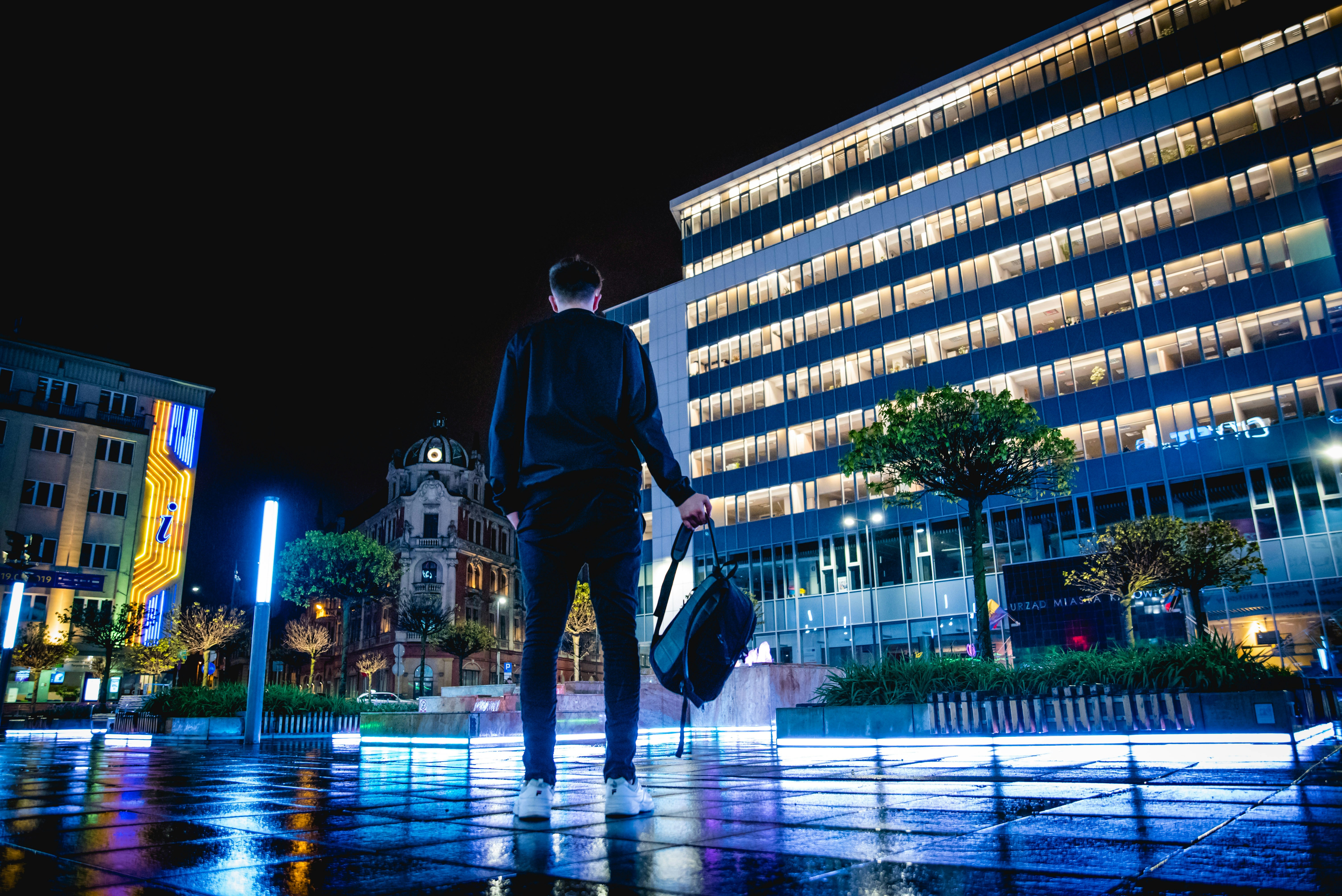 man standing on ground holding backpack