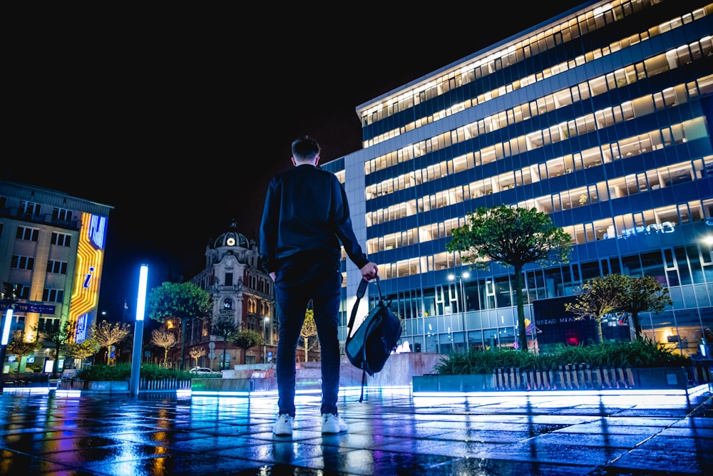 man standing on ground holding backpack