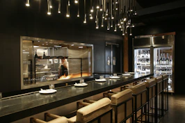 Elegant chef consulting with clients in a sleek, modern kitchen environment.