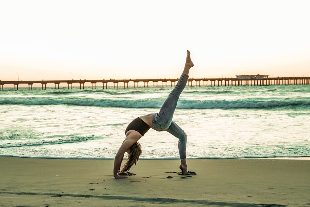 Frau macht Yoga-Pose am Meeresufer