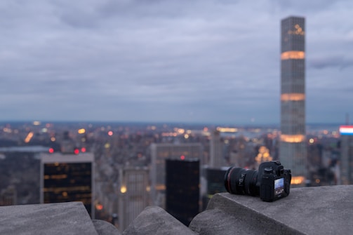 A modern mirrorless camera set against a backdrop of vibrant city lights at dusk.