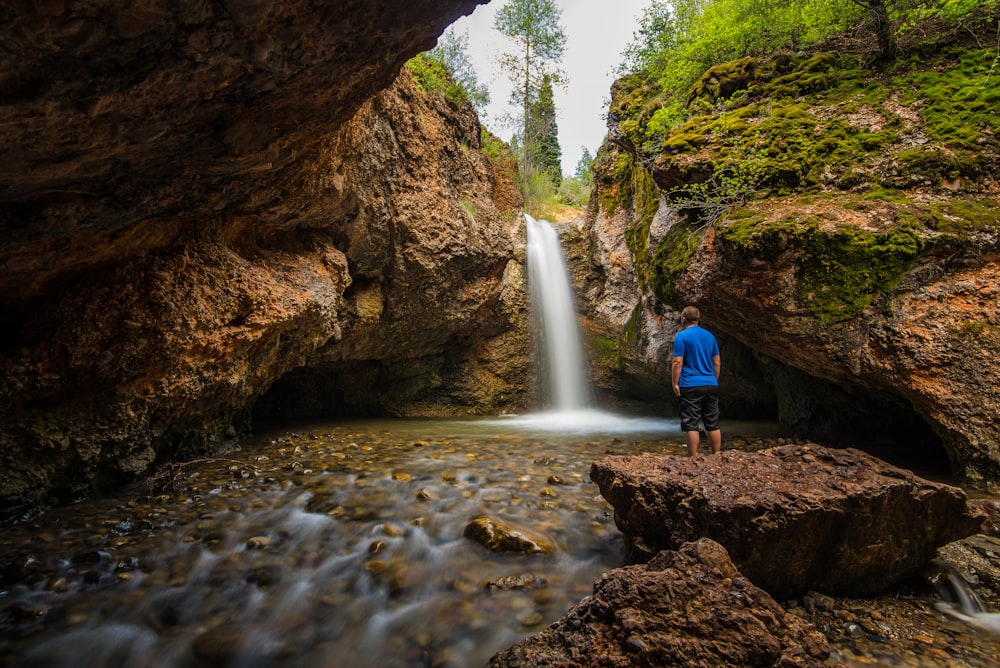 man standing near waterfall